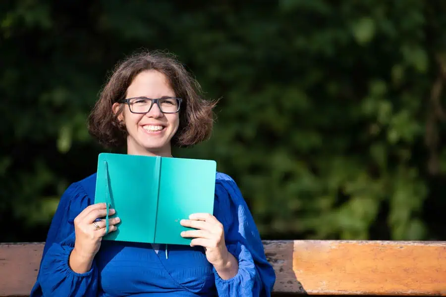 Marie Meyer Marktl hält ein Notizbuch hoch