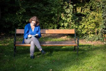 Marie Meyer-Marktl sitzt auf einer Bank und schreibt